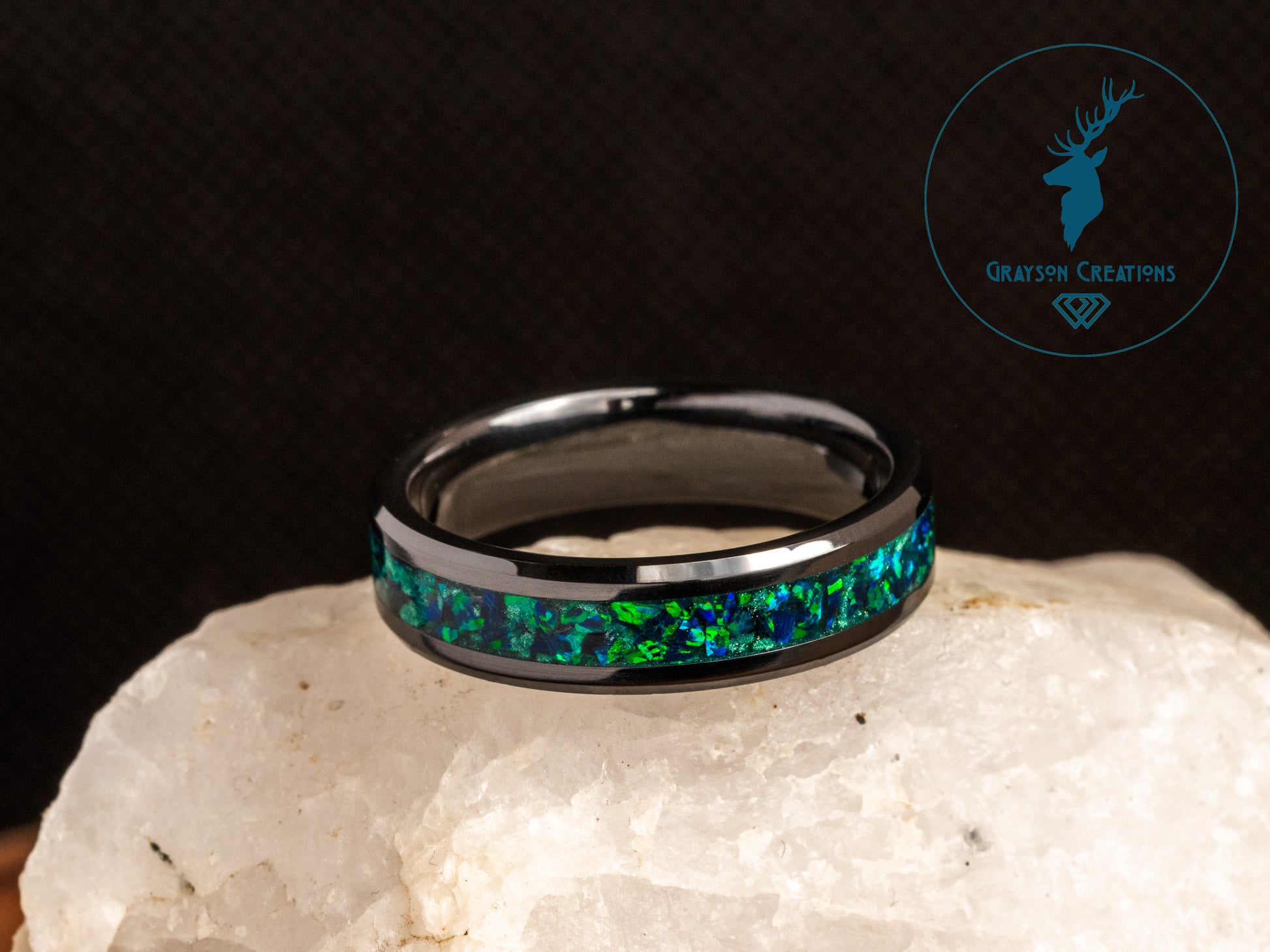 a ring with a green and blue design on top of a rock