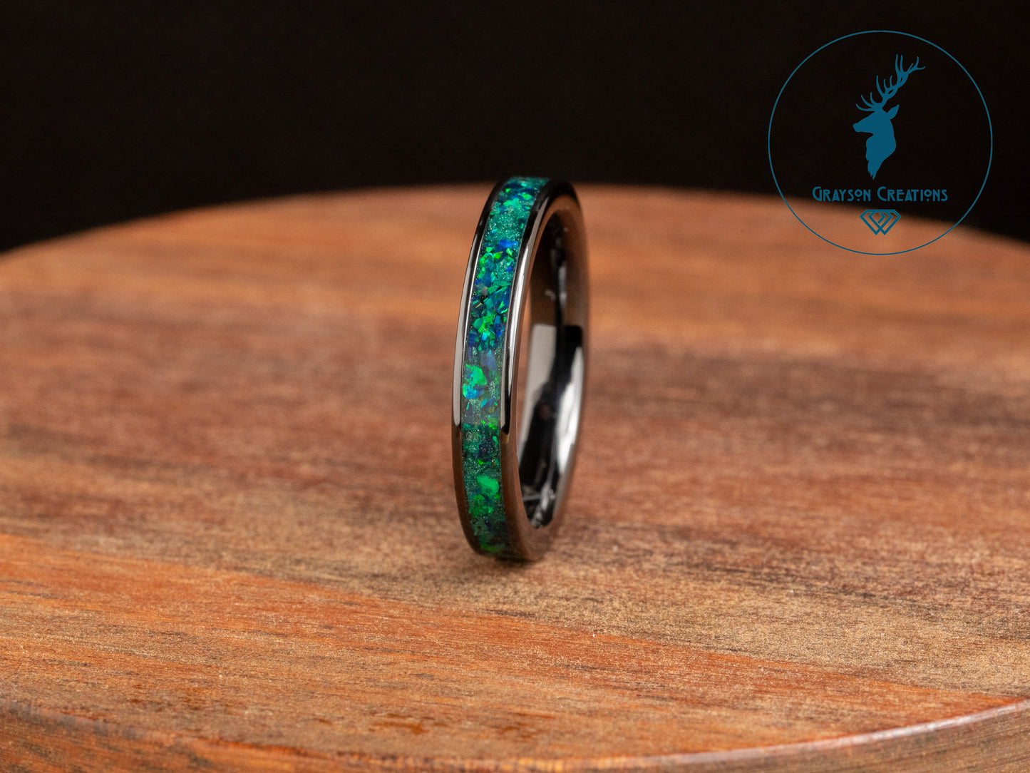 a ring with a green opal inlay sitting on top of a wooden table